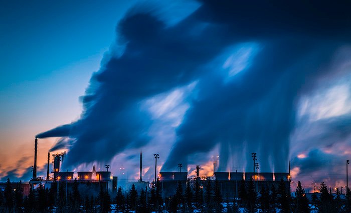 Smoke billowing from cooling towers of a refinery photographed at dawn